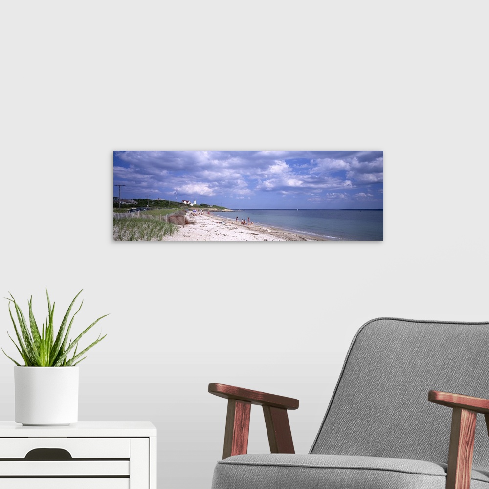 A modern room featuring A wide angle photograph is taken of a beach in Cape Cod that only has a few people on it. A light...