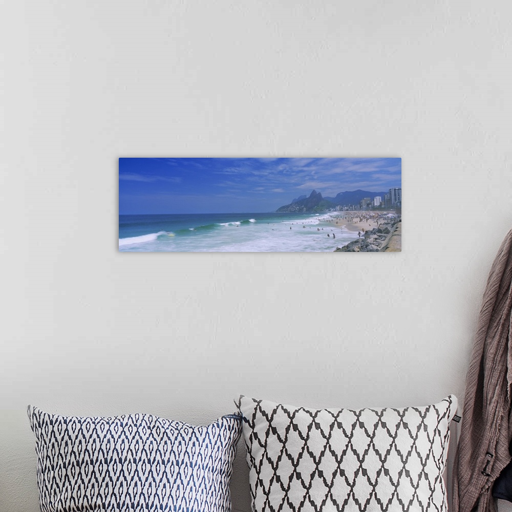 A bohemian room featuring Panoramic photo on canvas of a crowded beach in Brazil with waves crashing ashore.