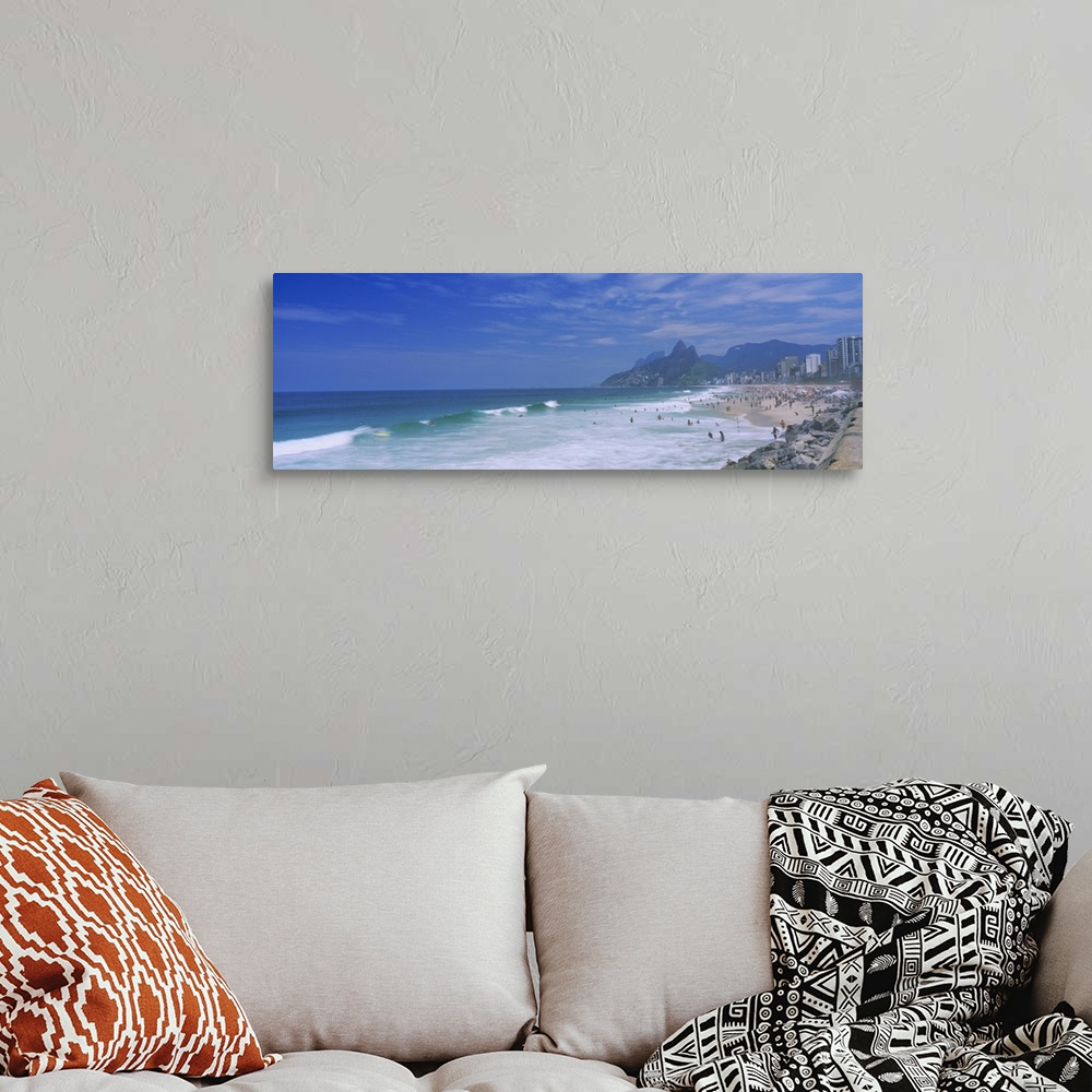 A bohemian room featuring Panoramic photo on canvas of a crowded beach in Brazil with waves crashing ashore.