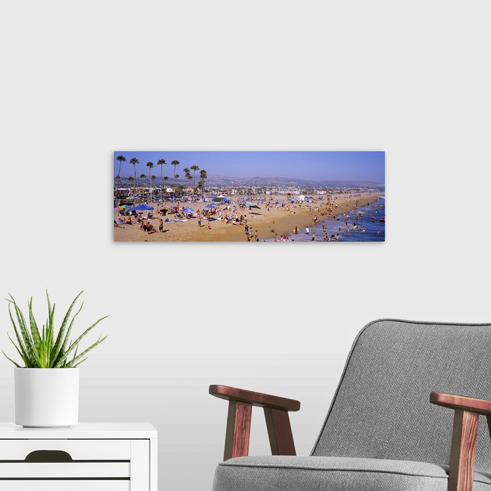 A modern room featuring Panoramic photograph of Newport Beach in California, crowded with people, palm trees and the city...