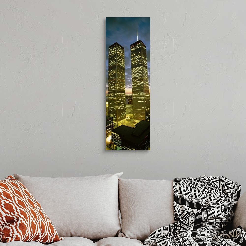A bohemian room featuring Panoramic photograph focuses on the nicknamed ""Twin Towers"" lit up at nighttime.  At the base o...