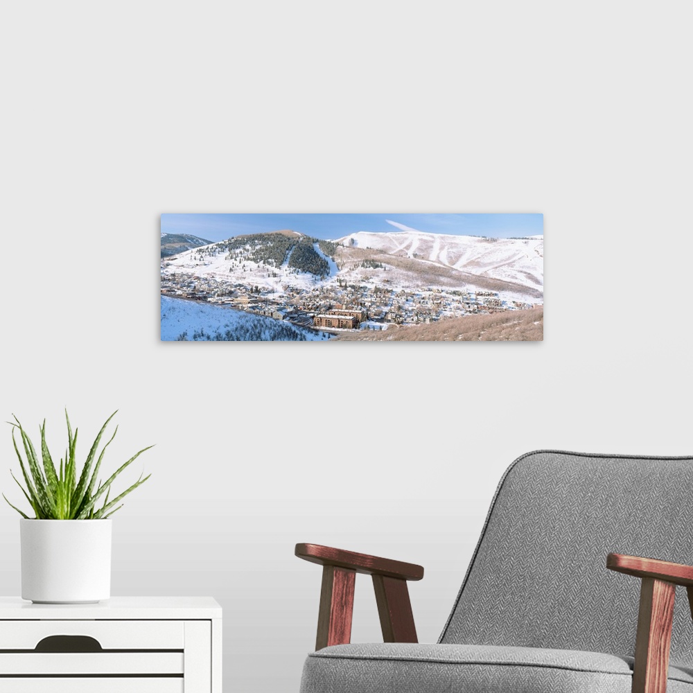 A modern room featuring Wide angle photograph on a large canvas of a distant town in a valley, surrounded by a snow cover...