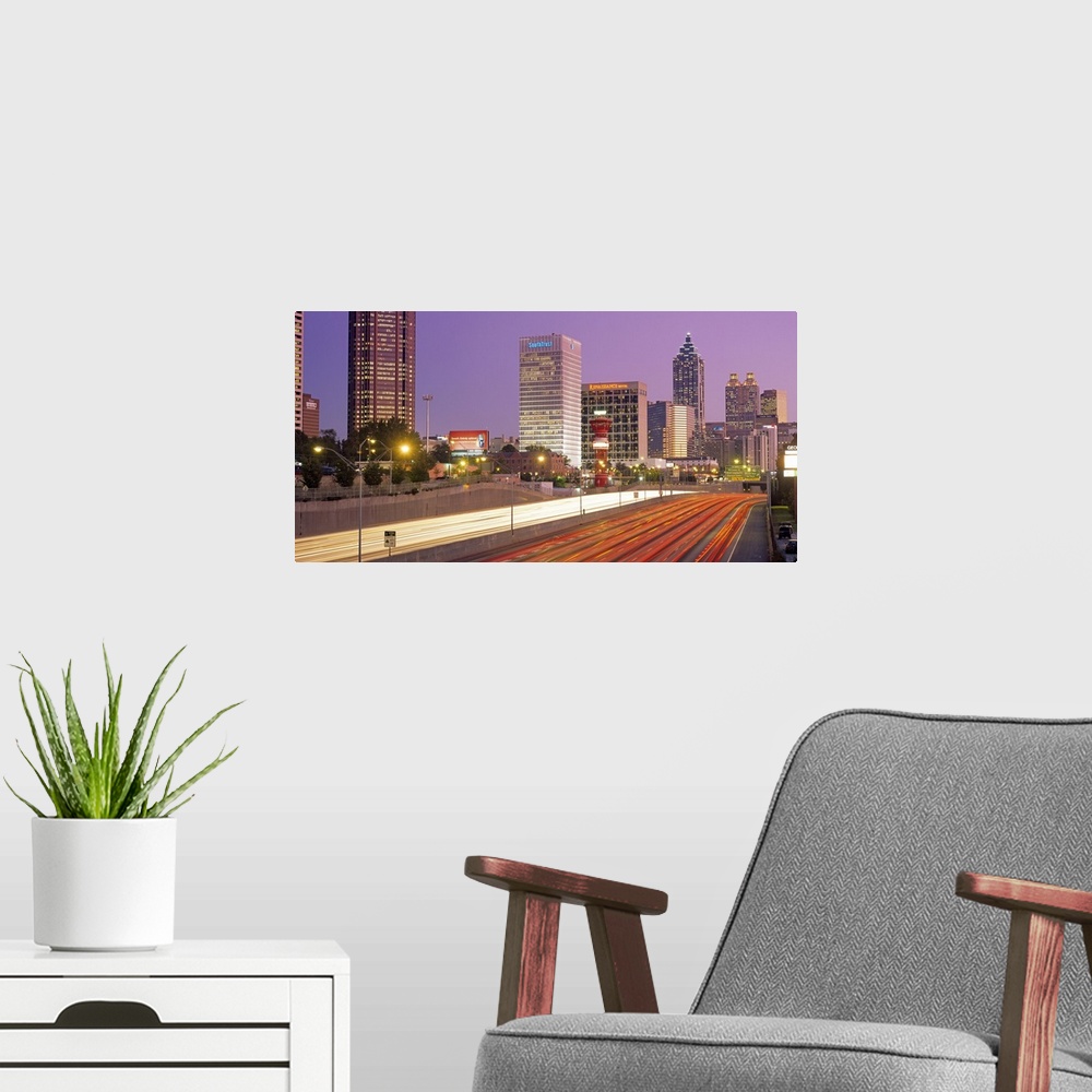 A modern room featuring Panoramic photograph of highway filled with light trails lined by lit up buildings at sunset.