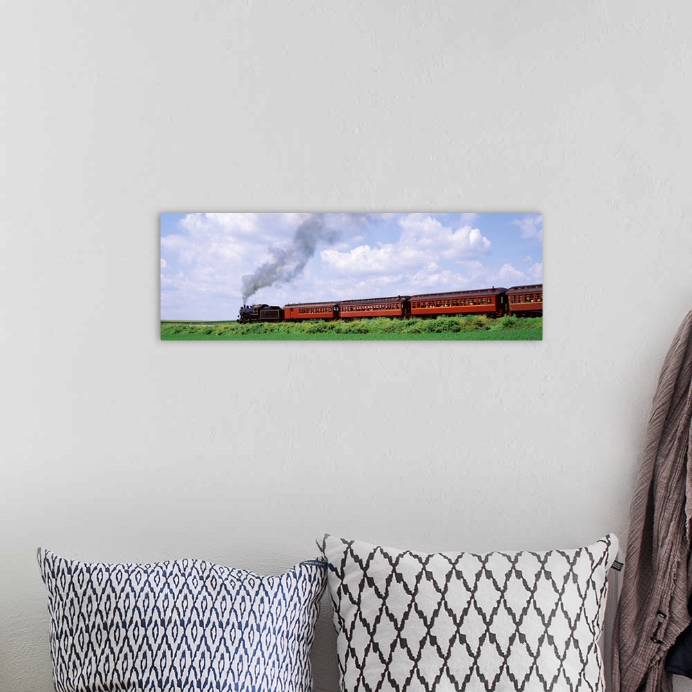 A bohemian room featuring Panoramic photograph on a large canvas of a steam train with red cars moving down a track surroun...