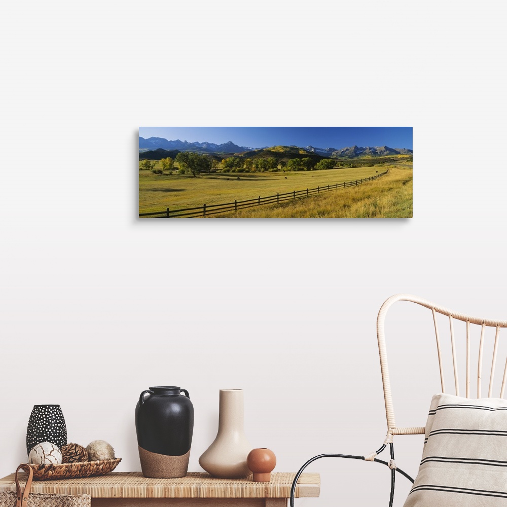 A farmhouse room featuring Wide angle photograph on a giant canvas of a wooden fence running alongside an vast field with tr...