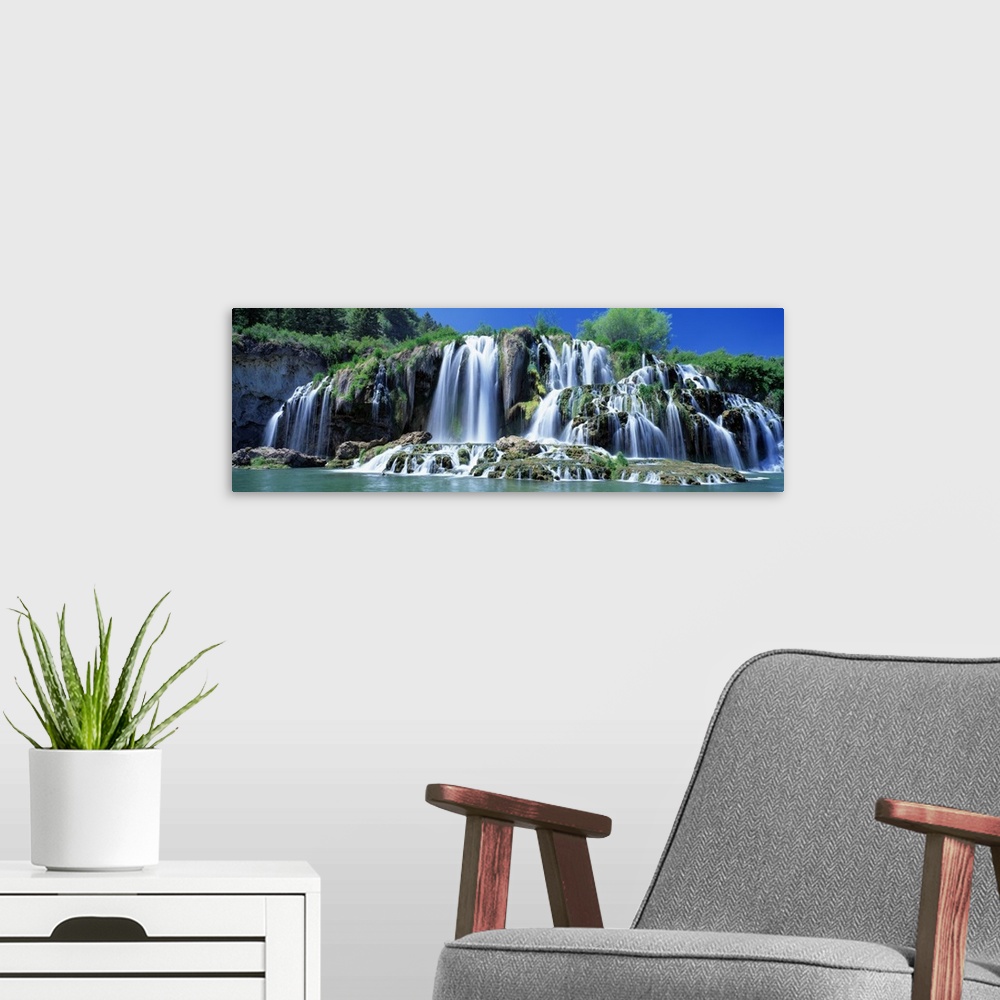 A modern room featuring Wide angle photograph of Tributary Waterfall, beneath a blue sky, pouring into the Snake River in...