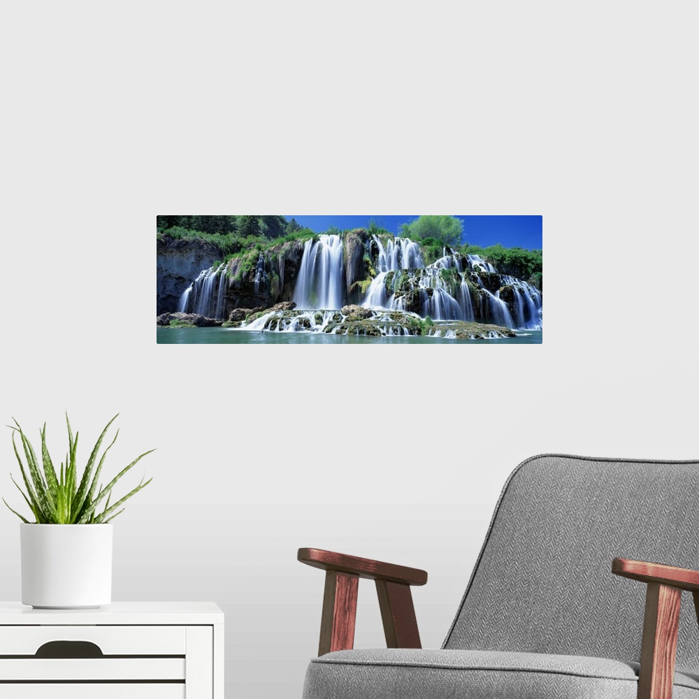 A modern room featuring Wide angle photograph of Tributary Waterfall, beneath a blue sky, pouring into the Snake River in...