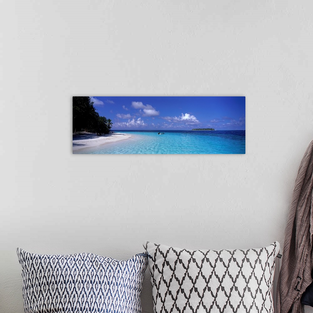 A bohemian room featuring This wide angle photograph is taken of clear ocean water that has a single boat sitting in it wit...