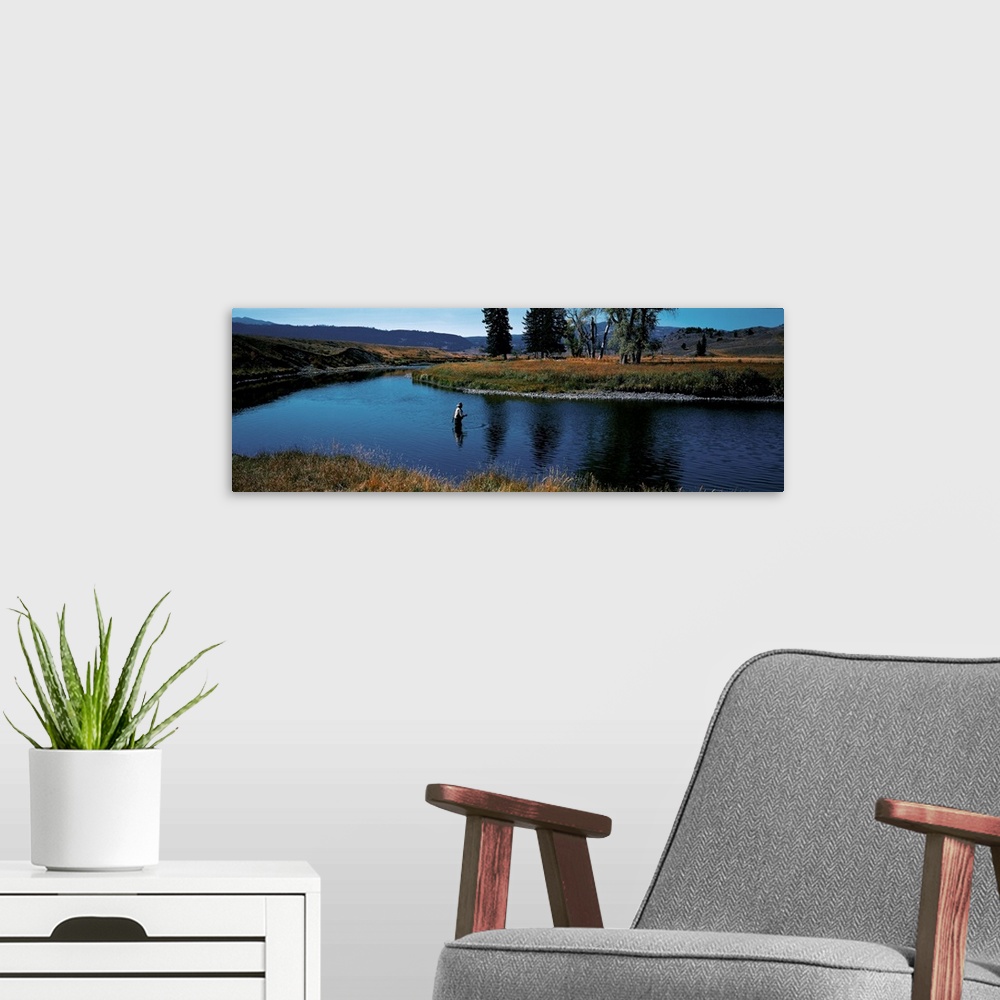 A modern room featuring Giant, landscape photograph of Slough Creek in Yellowstone National Park in Wyoming, surrounded b...