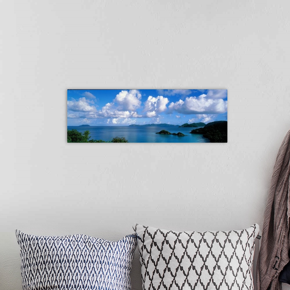 A bohemian room featuring Panoramic photograph of ocean sprinkled with small grass covered islands under a cloudy sky.