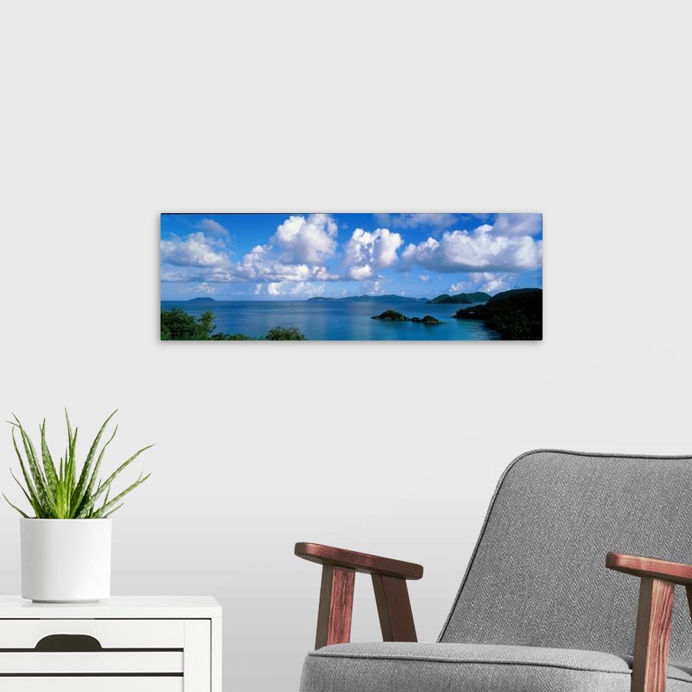 A modern room featuring Panoramic photograph of ocean sprinkled with small grass covered islands under a cloudy sky.