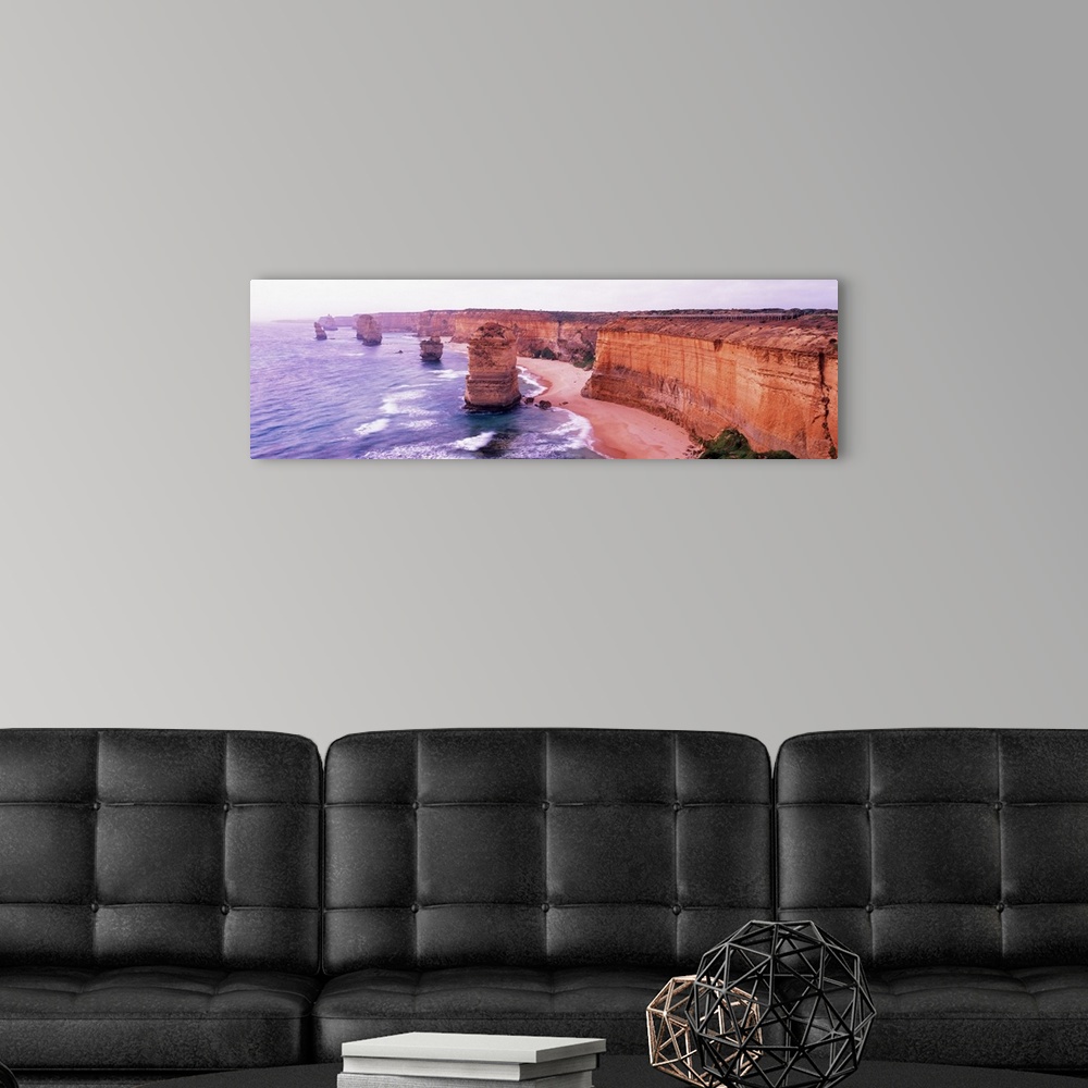A modern room featuring Pano of the Twelve Apostles sticking out of the Tasman Sea as the waves crash on to the sandy sho...