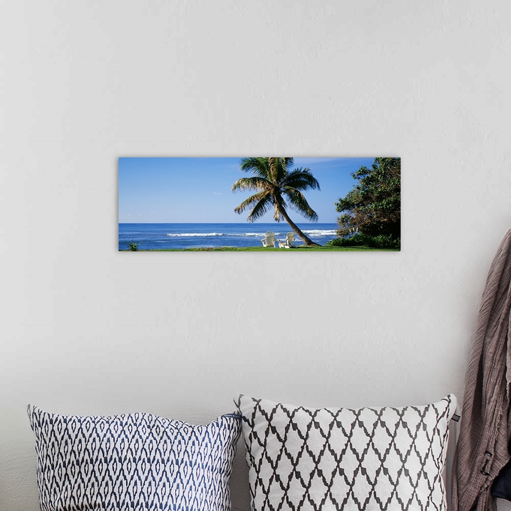 A bohemian room featuring This is a panoramic photograph of a grassy lawn that grows up the shoreline where two lounge chai...