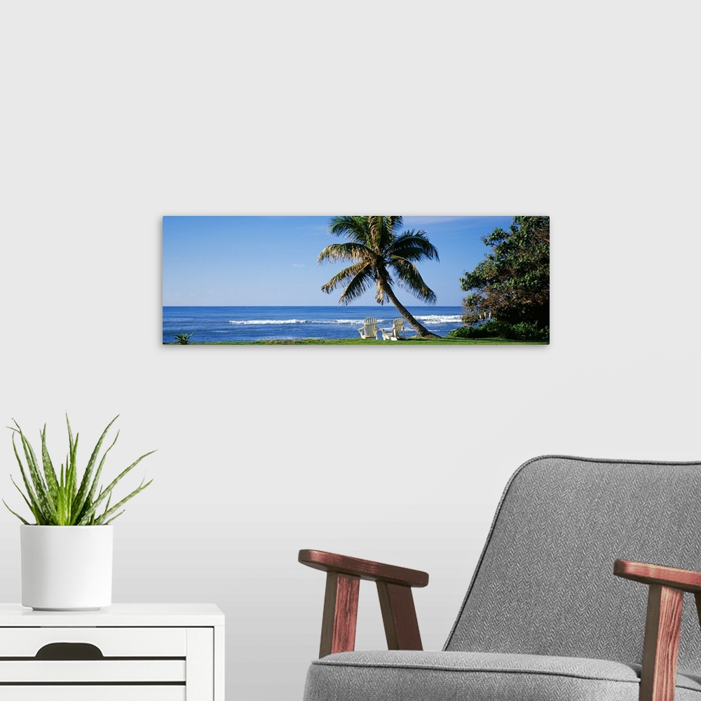 A modern room featuring This is a panoramic photograph of a grassy lawn that grows up the shoreline where two lounge chai...
