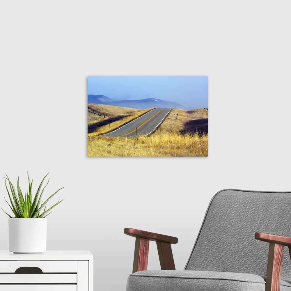 A modern room featuring Two lane highway through autumn color grasses, distant mountains in mist, Montana