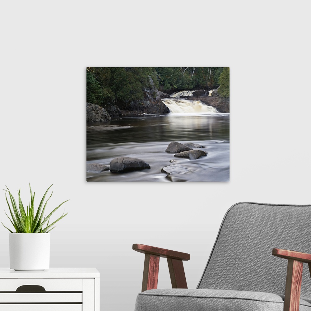 A modern room featuring Photograph of two falls flowing into a river that is lined with cliffs and trees on the back side...