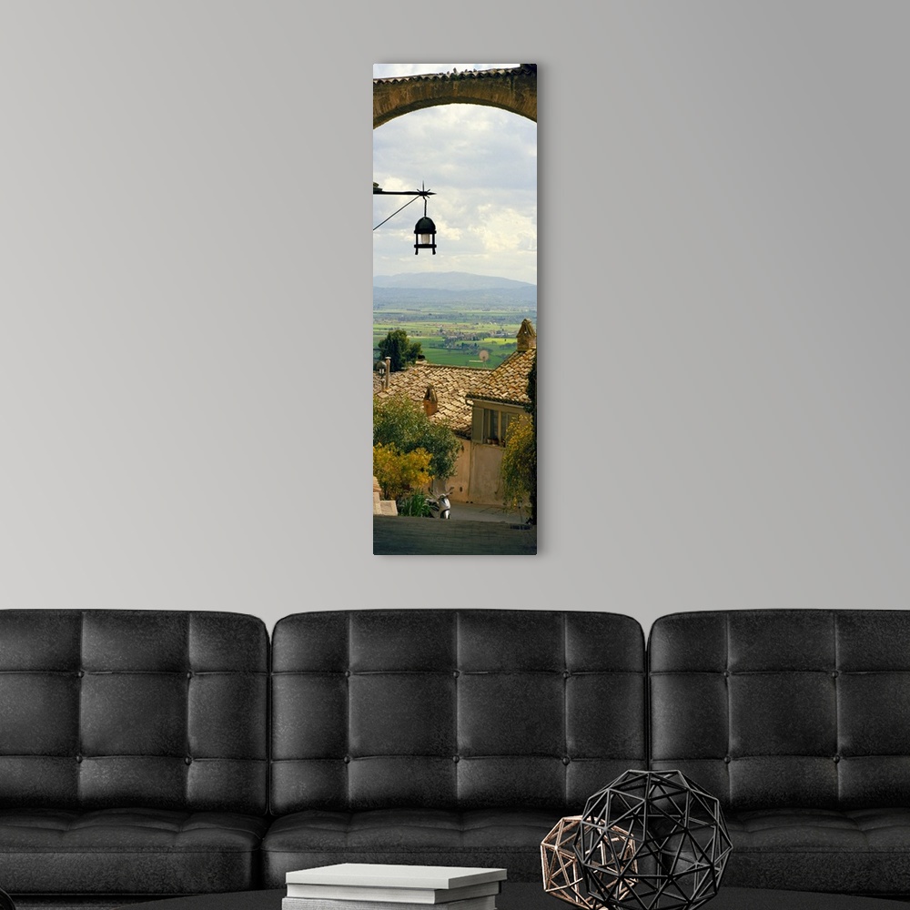 A modern room featuring Vertical panoramic photograph of tree tops and roofs with an open meadow and mountains in the dis...