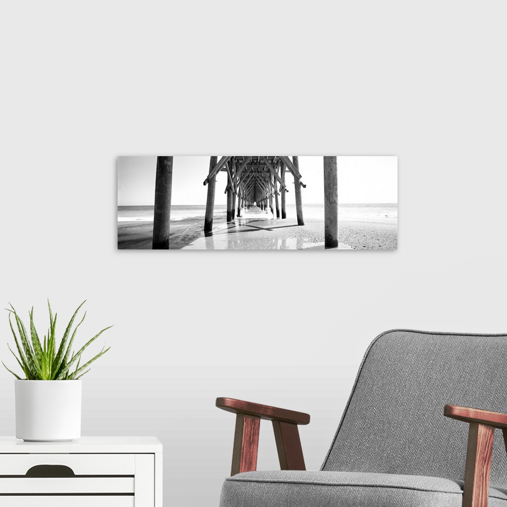 A modern room featuring Horizontal, huge, black and white panoramic photograph taken under a wooden pier, looking out tow...