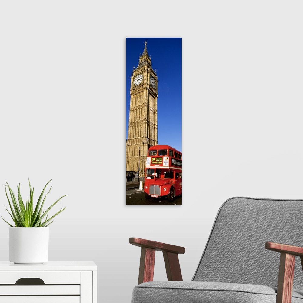 A modern room featuring Vertical shot of Big Ben and a red London city bus driving by.
