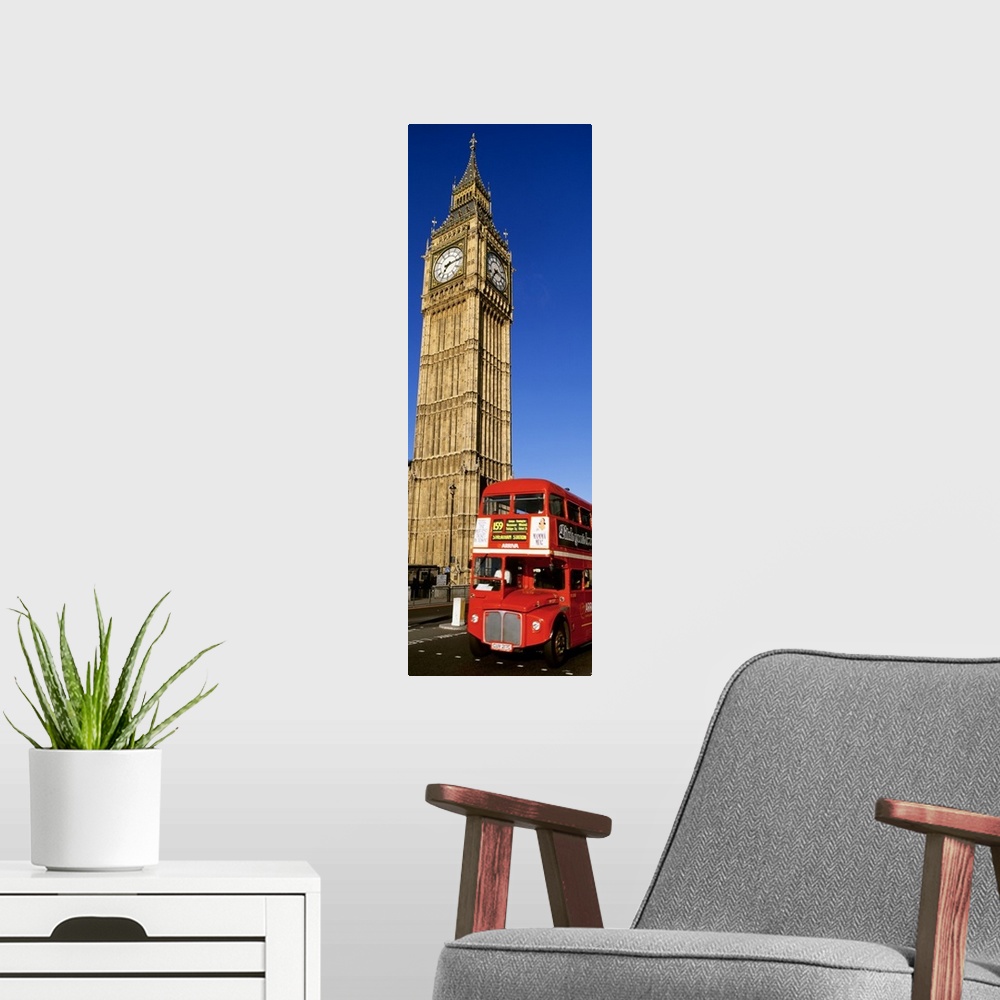A modern room featuring Vertical shot of Big Ben and a red London city bus driving by.