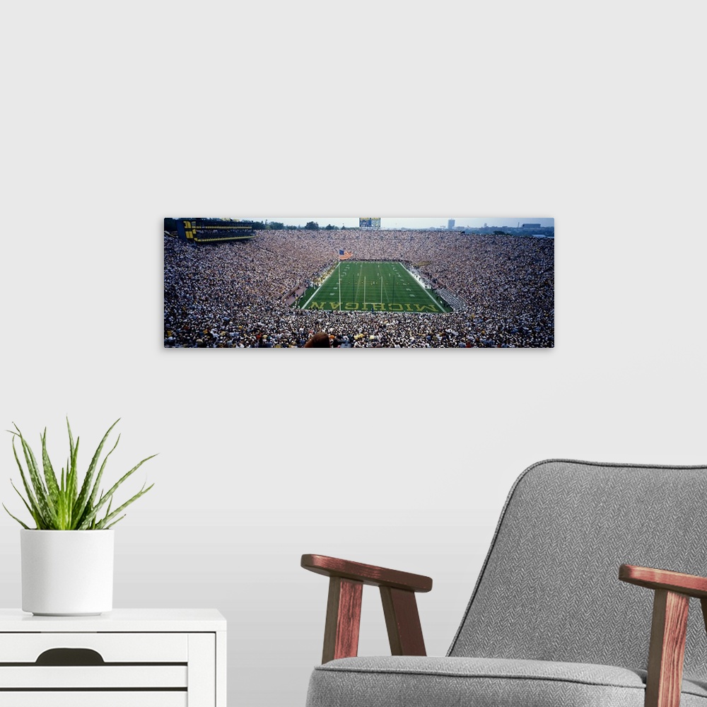 A modern room featuring Wide angle, aerial photograph of Michigan Stadium full of fans, during a University of Michigan f...
