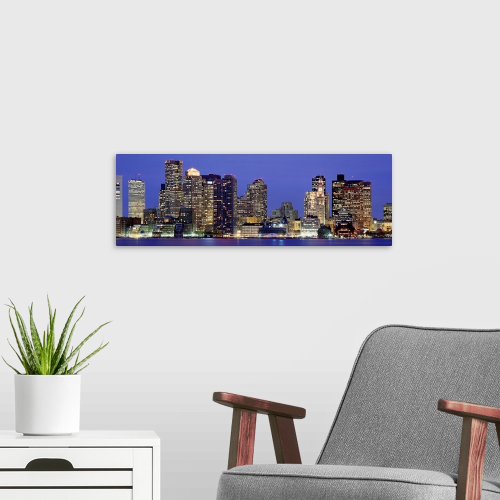 A modern room featuring A panoramic photograph taken from the water of sky scrapers in the dark.