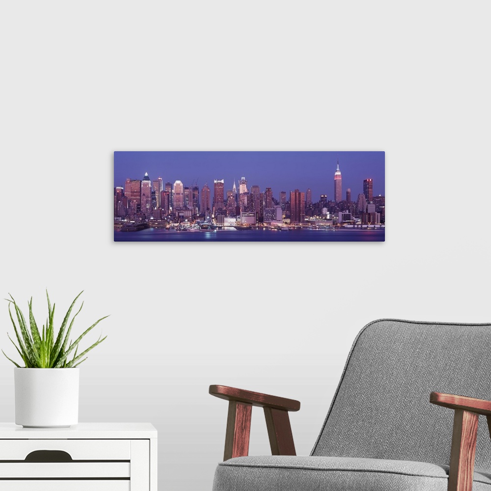 A modern room featuring Panoramic photograph of skyline and waterfront at night with buildings lit up and lights reflecte...