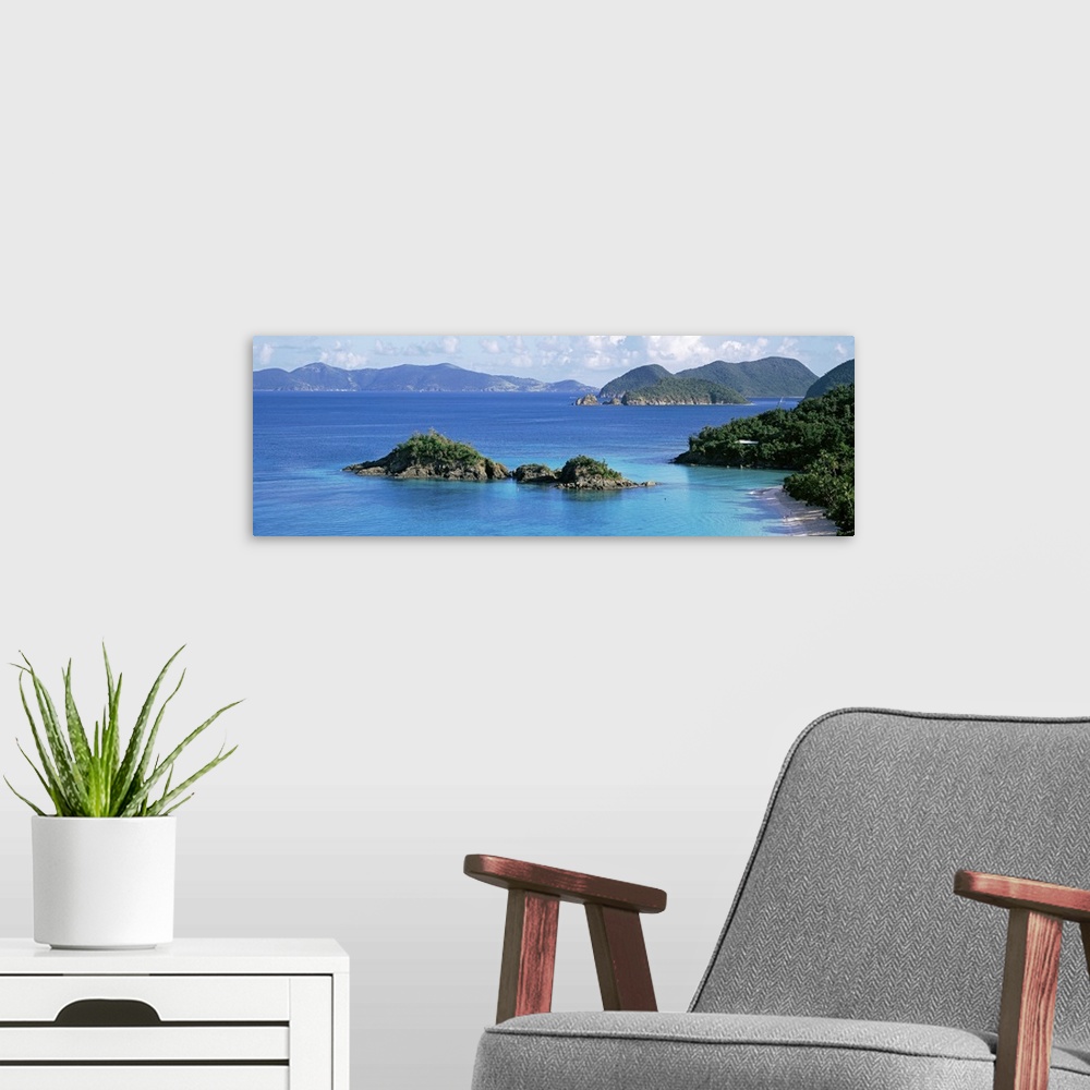 A modern room featuring This decorative wall is a panoramic landscape photograph of a small rocky island off the shore of...