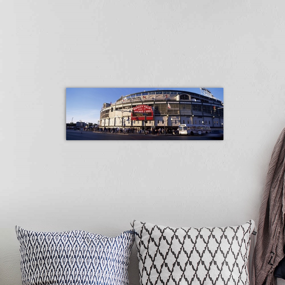 A bohemian room featuring Wrigley Field is photographed in wide angle view with crowds standing in the front of the stadium...