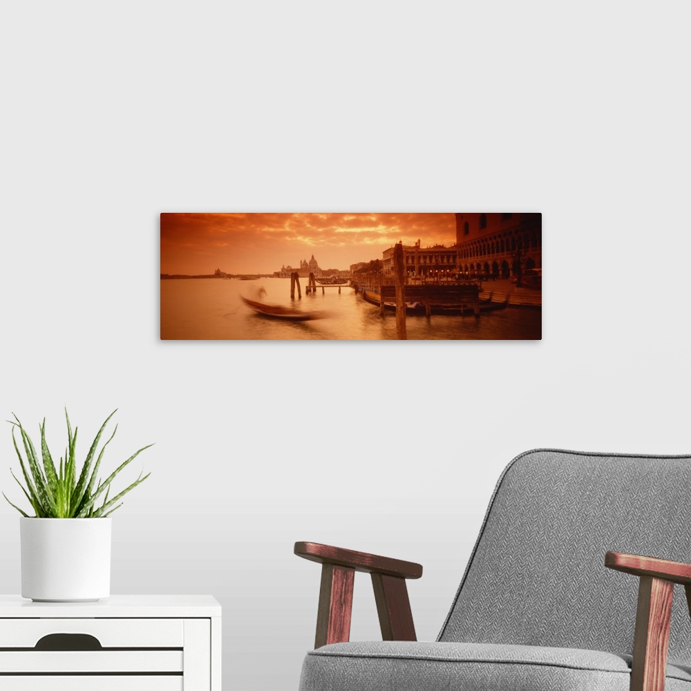 A modern room featuring Panorama of a small Italian harbor with a blurred gondola coming into port at sunset.