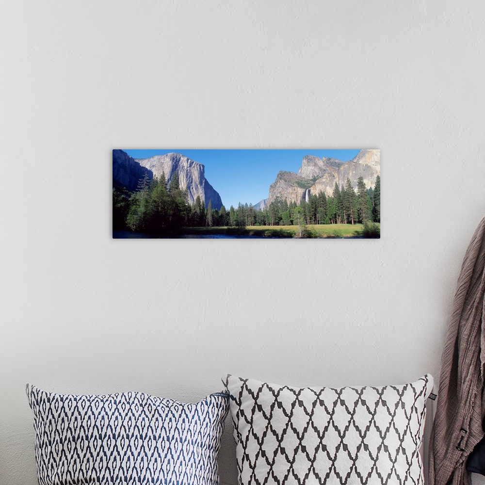 A bohemian room featuring Panoramic photo of large rock cliffs and mountings surrounded by pine trees and water in Yosemite...