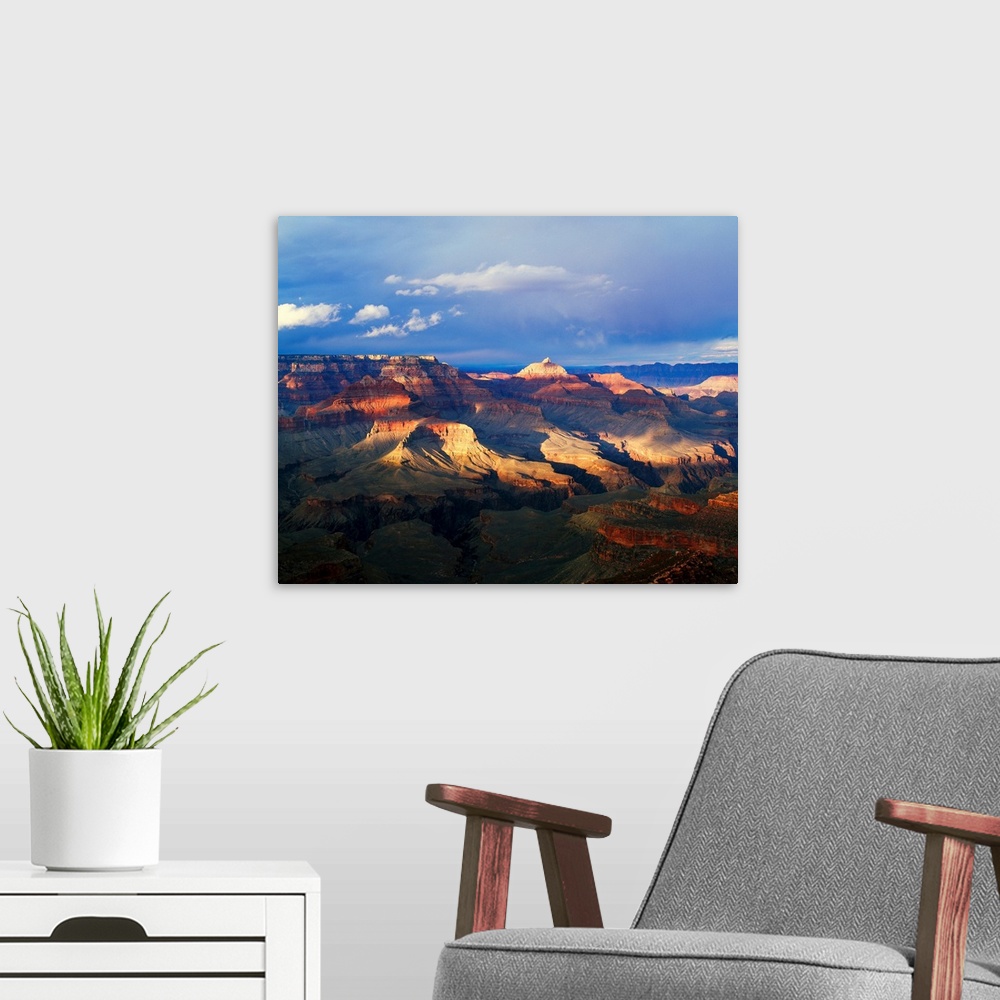 A modern room featuring This landscape photograph captures the light passing through the approaching storm and hitting th...