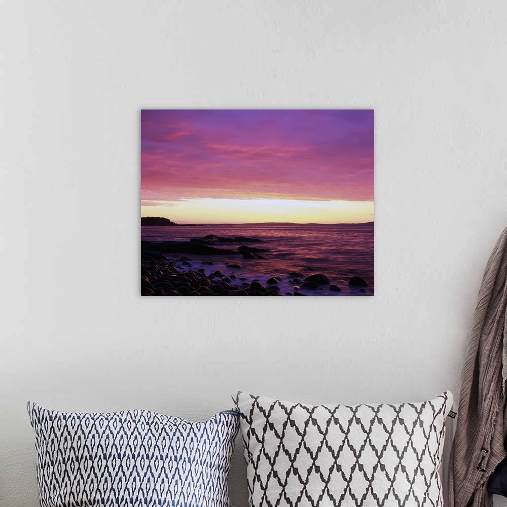 A bohemian room featuring This large piece is a picture taken of the sun rise off the coast of Maine. Rocks line the edge o...