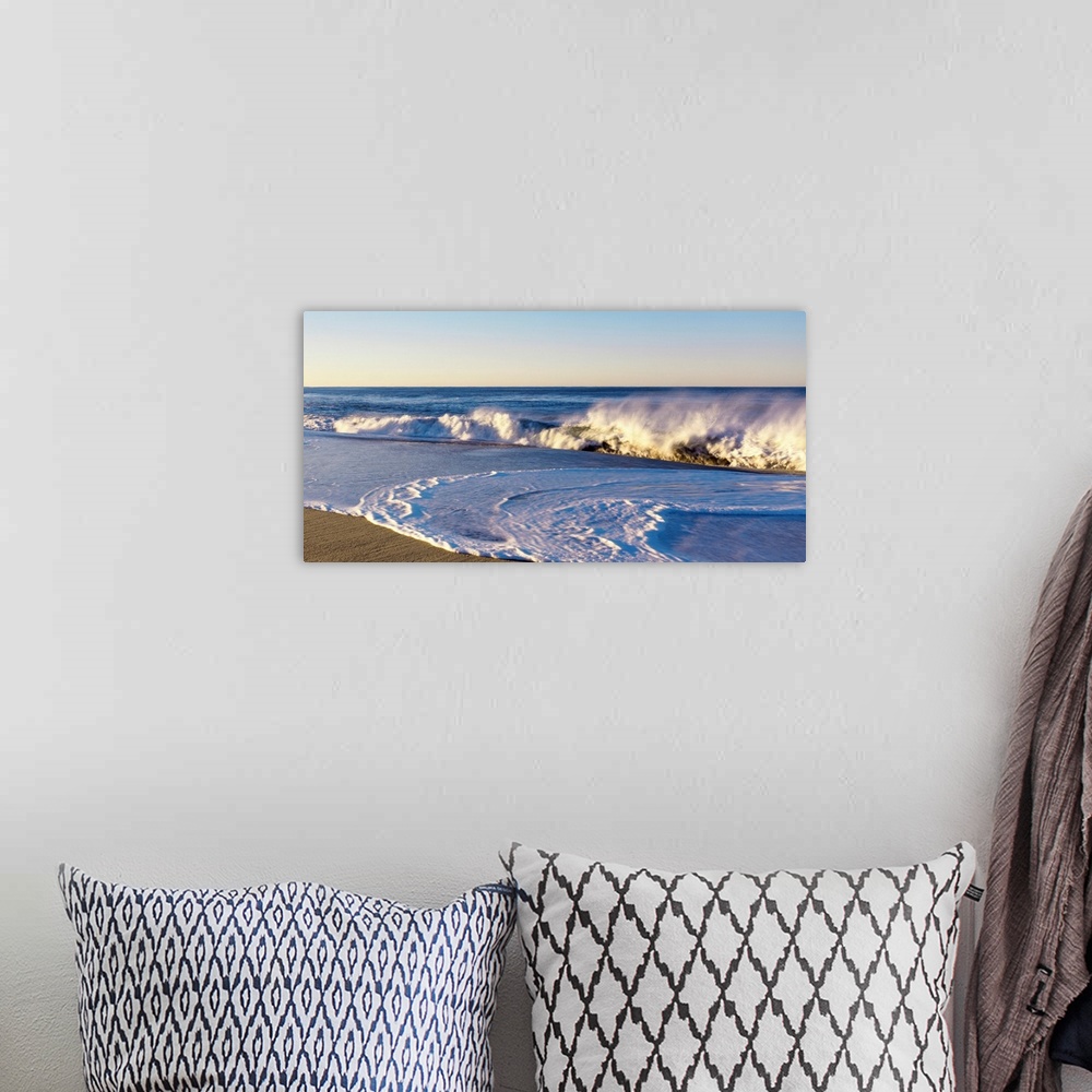 A bohemian room featuring This landscape photograph shows waves curling and crashing into a sandy beach in the late afternoon.