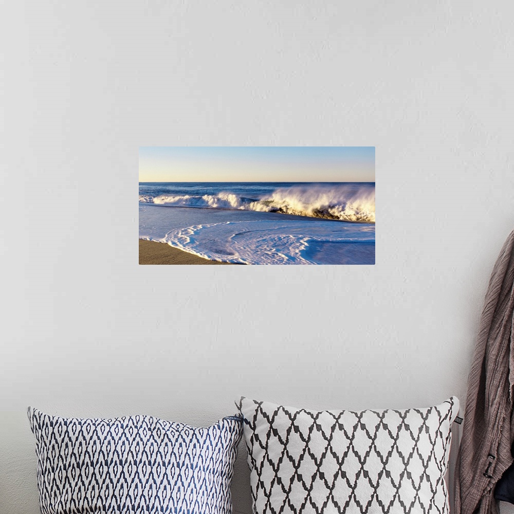 A bohemian room featuring This landscape photograph shows waves curling and crashing into a sandy beach in the late afternoon.