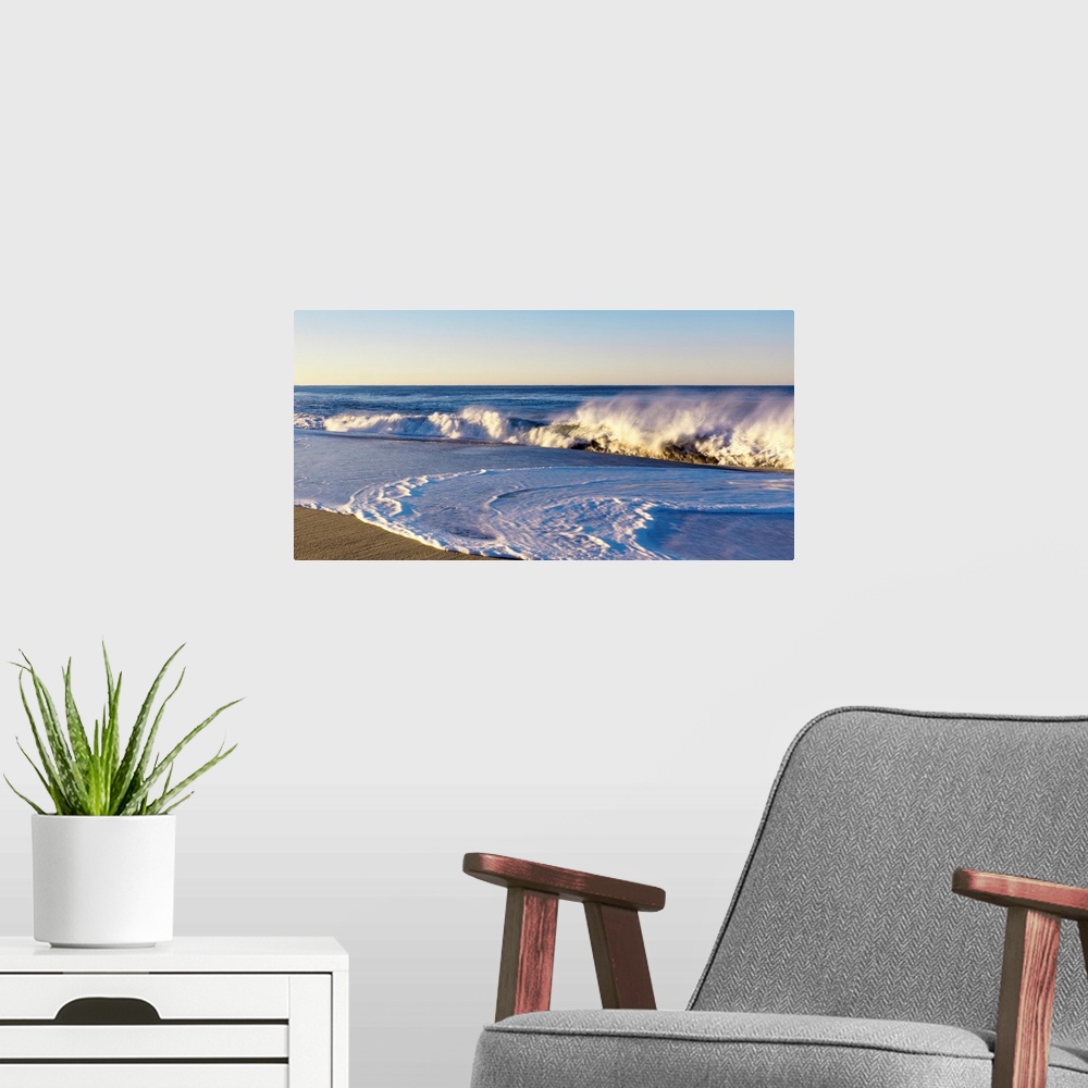 A modern room featuring This landscape photograph shows waves curling and crashing into a sandy beach in the late afternoon.