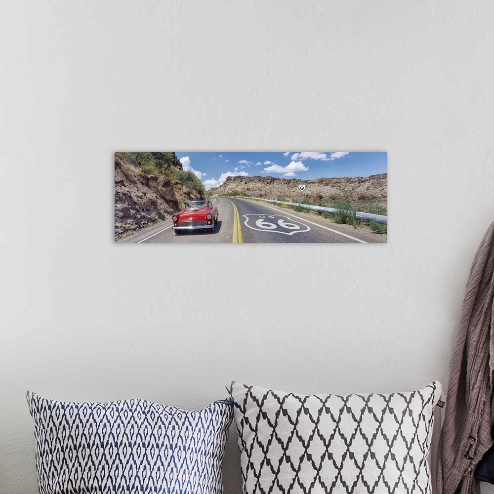 A bohemian room featuring Panoramic photograph of classic car on highway winding through the mountains under a cloudy sky.