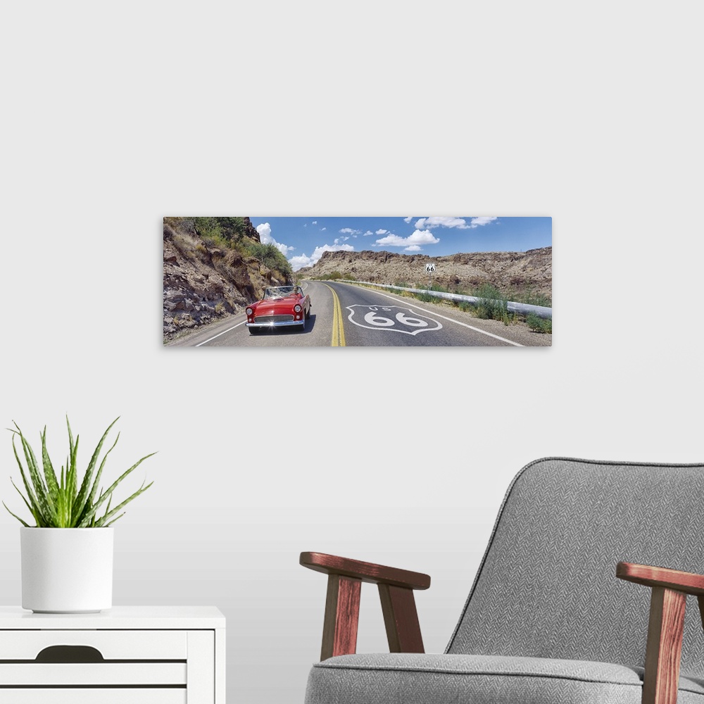 A modern room featuring Panoramic photograph of classic car on highway winding through the mountains under a cloudy sky.