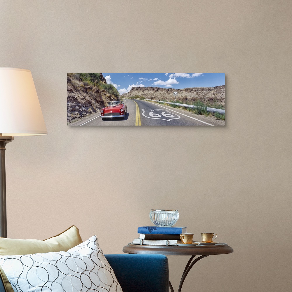 A traditional room featuring Panoramic photograph of classic car on highway winding through the mountains under a cloudy sky.