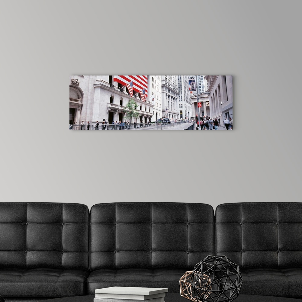 A modern room featuring Large panoramic photograph of wall street in NYC with people walking on the sidewalk and a large ...