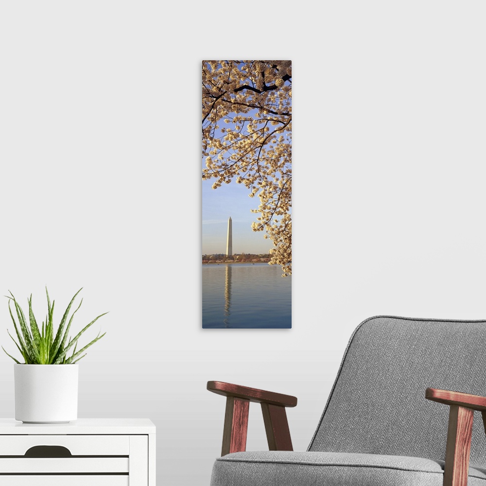 A modern room featuring Vertical, oversized photograph of  the branches of a cherry blossom tree in bloom, hanging over t...