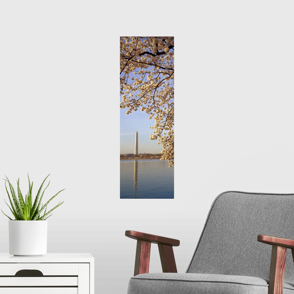 A modern room featuring Vertical, oversized photograph of  the branches of a cherry blossom tree in bloom, hanging over t...