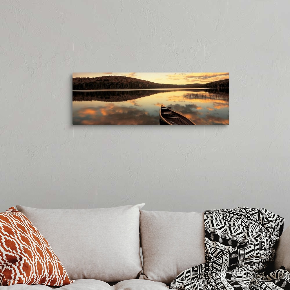 A bohemian room featuring A canoe floats in a still lake at sunset in New England as clouds reflect in the water.