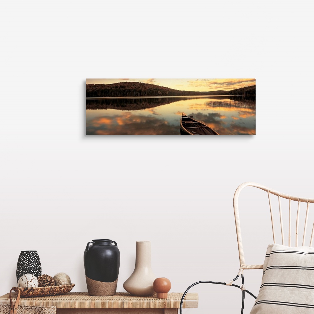 A farmhouse room featuring A canoe floats in a still lake at sunset in New England as clouds reflect in the water.