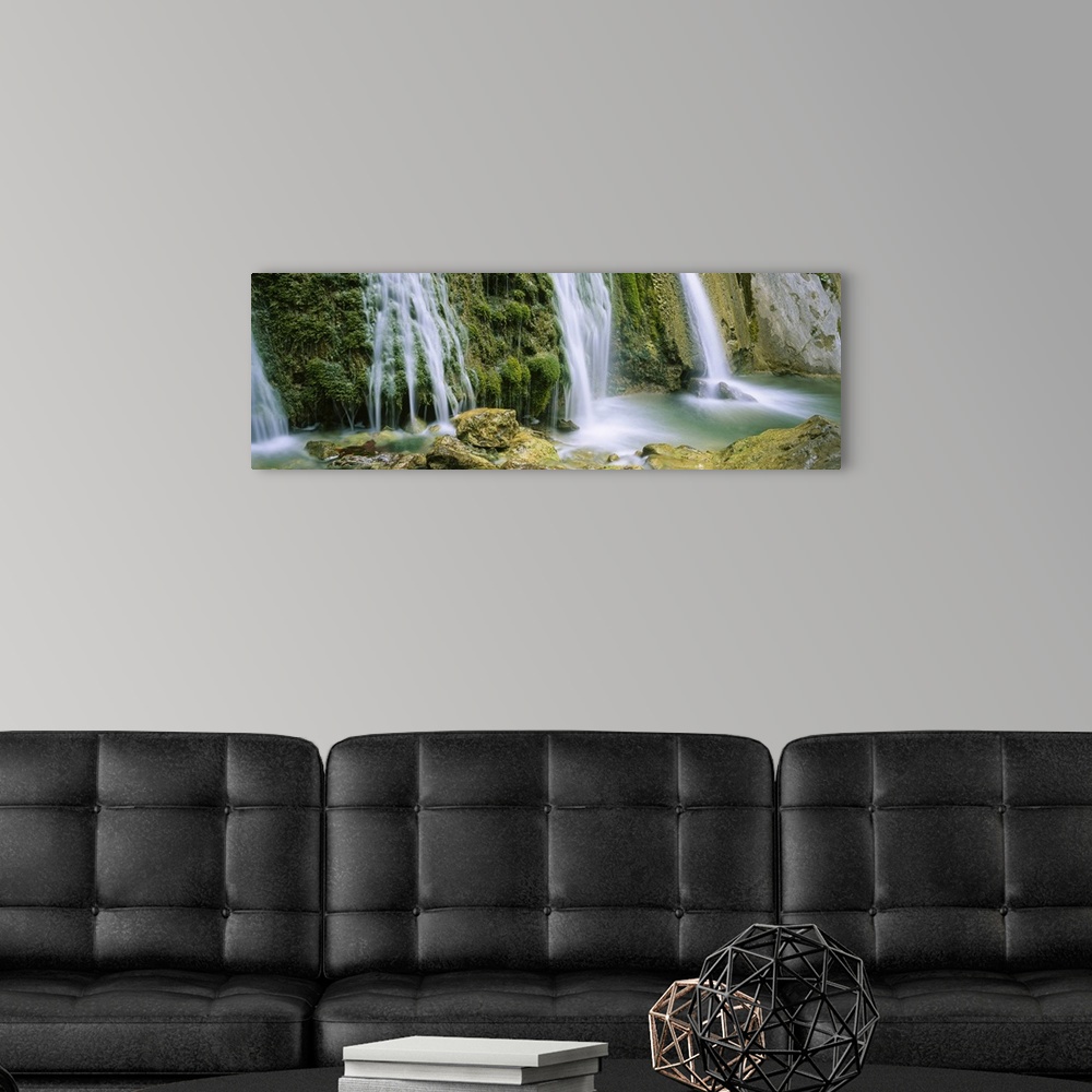 A modern room featuring Panoramic photograph taken of several waterfalls cascading over foliage and crashing onto rocks.