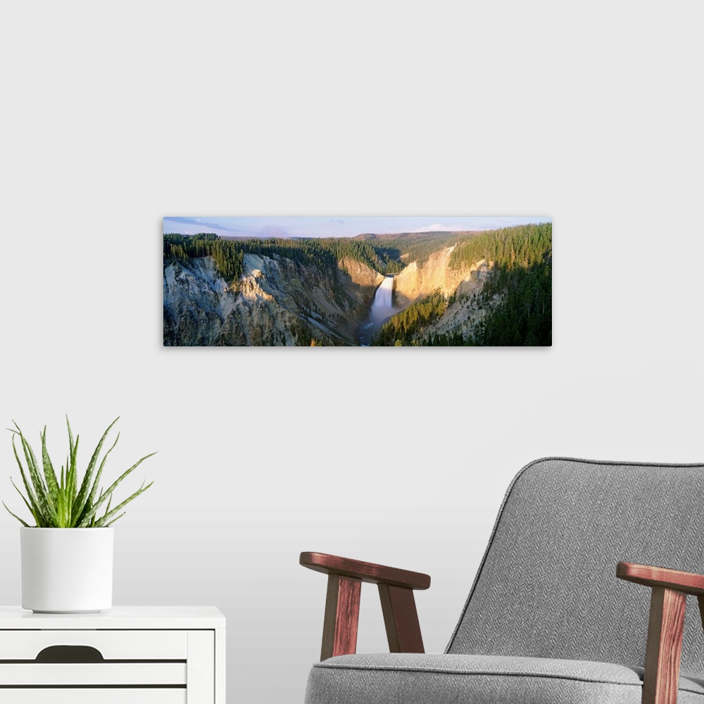 A modern room featuring Panoramic photograph of waterfall flowing through valley surrounded by snow and tree covered moun...