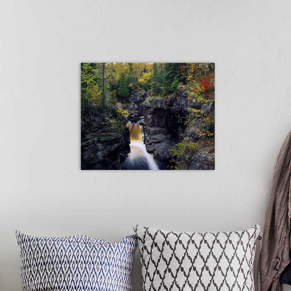 A bohemian room featuring Landscape photograph of a fall colored forest on top of tall rocky cliffs that rise above a water...