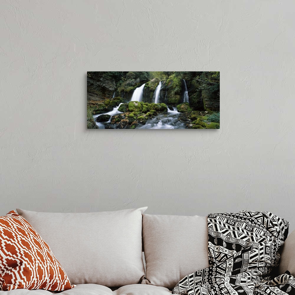 A bohemian room featuring Panoramic photograph of water cascading over rocks flowing into rocky moss covered stream below.