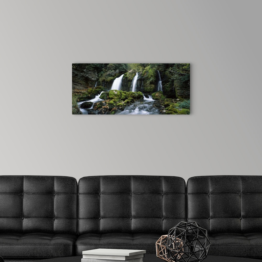 A modern room featuring Panoramic photograph of water cascading over rocks flowing into rocky moss covered stream below.