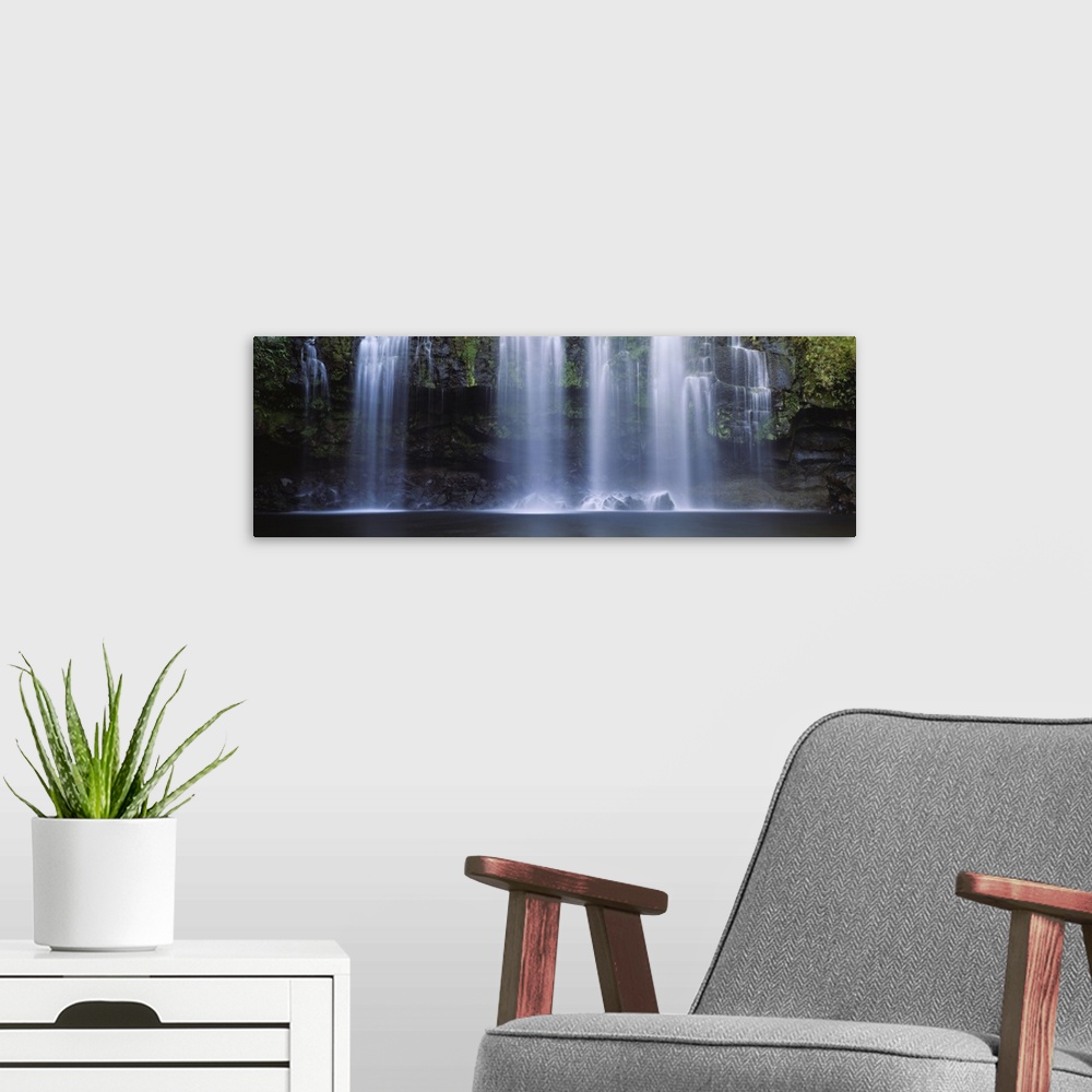 A modern room featuring Multiple cascades fall over a moss covered rock face into a pool in this panoramic photograph of ...